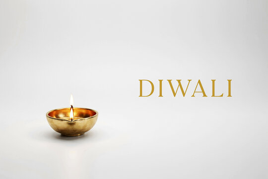 A glowing golden traditional Indian oil lamp or diya with a vibrant burning flame accompanied by the elegant golden text DIWALI creating a festive and spiritual atmosphere for the joyous celebration
