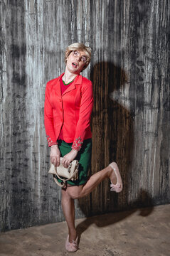 Smirking creepy woman stands against grunge dark wall