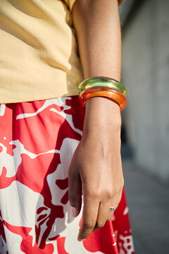 Vertical shot of young adult woman hand wearing chunky bangles and ring, showcasing fashion accessories and personal style. Ideal for jewelry marketing, retail ads