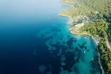 Fototapeta premium Aerial summer landscape of a turquoise lagoon on Thassos Island, Greece, showing crystal clear water, beach, swimmers, paddleboards and rocky coastline. 