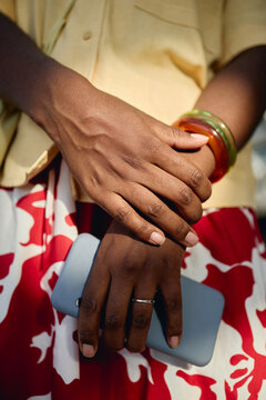 Vertical shot of Black young adult woman crossing hands while holding smartphone, signaling mobile lifestyle and personal communication. Ideal for digital life, messaging, connectivity themes