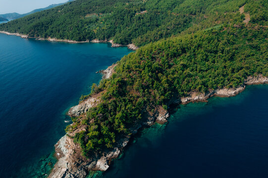 Aerial summer landscape of a turquoise lagoon on Thassos Island, Greece, showing crystal clear water, beach, swimmers, paddleboards and rocky coastline.	
