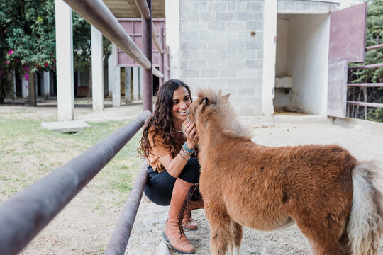 Latina woman taking care of a small pony in ranch in Mexico Latin America