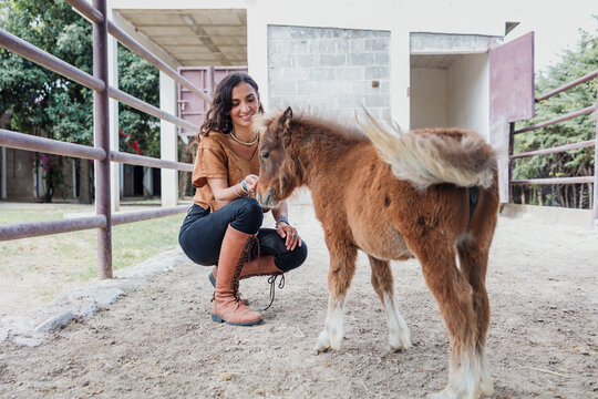 Latina woman taking care of a small pony in ranch in Mexico Latin America