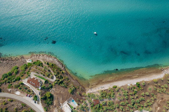 Aerial summer landscape of a turquoise lagoon on Thassos Island, Greece, showing crystal clear water, beach, swimmers, paddleboards and rocky coastline.
