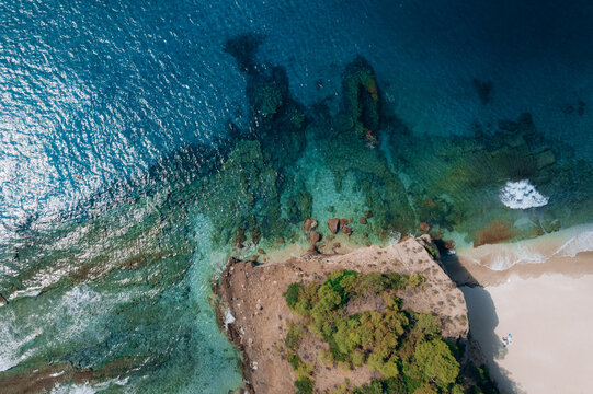Aerial summer landscape of a turquoise lagoon on Thassos Island, Greece, showing crystal clear water, beach, swimmers, paddleboards and rocky coastline.
