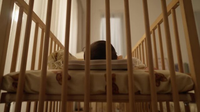 Close Up Low Angle of Baby Sleeping Soundly Inside Wooden Nursery Crib