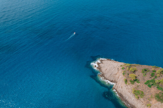 Aerial drone of a peaceful beach in Thassos, Greece, featuring transparent turquoise water, paddleboards, swimmers and a beautiful Mediterranean coastline.
