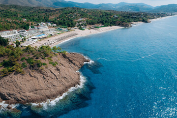 Fototapeta premium Aerial drone of a peaceful beach in Thassos, Greece, featuring transparent turquoise water, paddleboards, swimmers and a beautiful Mediterranean coastline. 