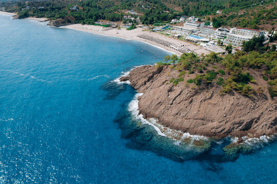 Aerial summer landscape of a turquoise lagoon on Thassos Island, Greece, showing crystal clear water, beach, swimmers, paddleboards and rocky coastline.