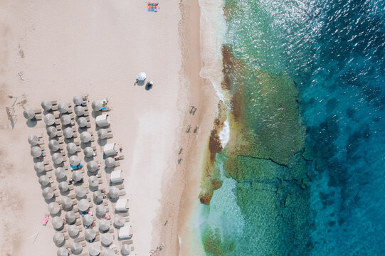 Aerial summer landscape of a turquoise lagoon on Thassos Island, Greece, showing crystal clear water, beach, swimmers, paddleboards and rocky coastline.