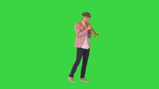 Young gifted street musician plays the trumpet masterly on a Green Screen, Chroma Key.