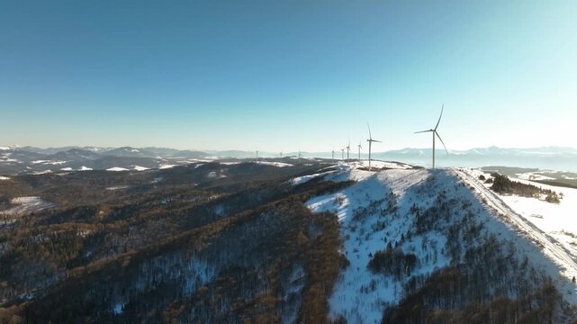 Panoramic aerial view of wind turbines on a snow-covered mountain range