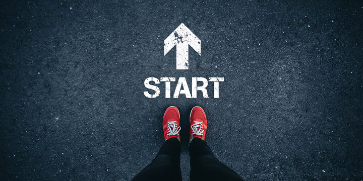 First step toward success with red sports sneakers standing at a painted white start arrow on asphalt motivation beginning movement lifestyle direction adventure ambition