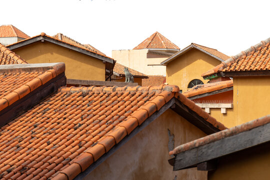 Orange clay tile roofs of Mediterranean style buildings with a cat statue on a ledge