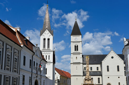 church bell towers in elevation view in the city of Veszprem in Hungary. white stucco exterior wall finish. steep sloped roofs. Christian cross on top. travel, tourism, architecture, religion concept