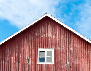 A classic Finnish wooden barn painted in traditional red ochre (punamulta) standing in the rural countryside of Vantaa, Finland, set against a dramatic, overcast cloudy sky. © Juha