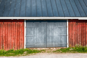 A classic Finnish wooden barn painted in traditional red ochre (punamulta) standing in the rural countryside of Vantaa, Finland, set against a dramatic, overcast cloudy sky. HDR. © Juha