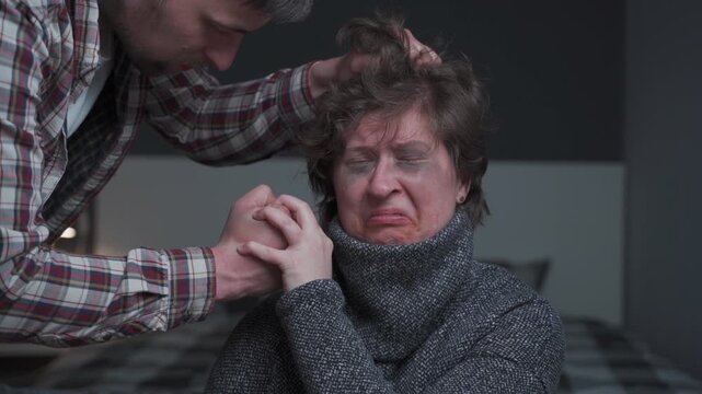A powerful scene of domestic abuse where a woman with visible bruises bravely resists her abuser. The man grabs her hair aggressively, but she courageously stops him, symbolizing defiance and strength