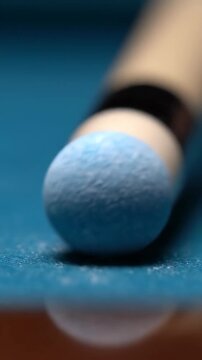 Close-up of a billiard cue tip on a blue pool table