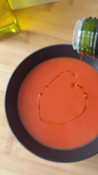 Adding olive oil to the salmorejo in the bowl