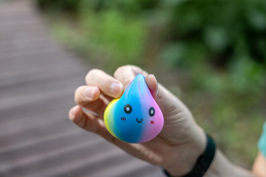 Hand holding blue and pink squishy stress relief toy outdoors