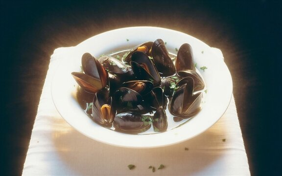 Zoom sur des moules marini&egrave;res dans une assiette sur une table avec une nappe blanche 