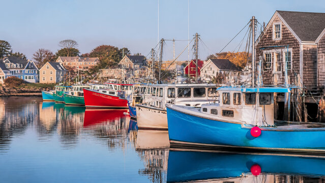 Colorful fishing boats docked in a serene harbor at sunrise, featuring traditional coastal architecture and calm reflective water, perfect for travel, maritime industry, and nautical lifestyle