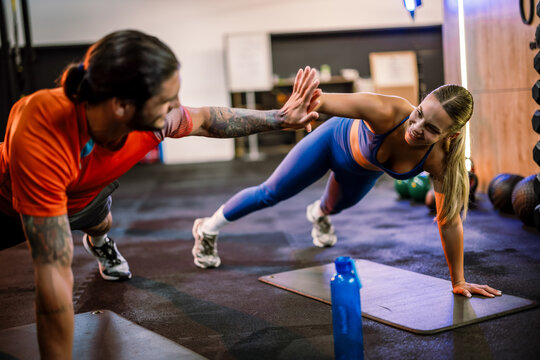 Fitness partners doing core plank and high five exercise together