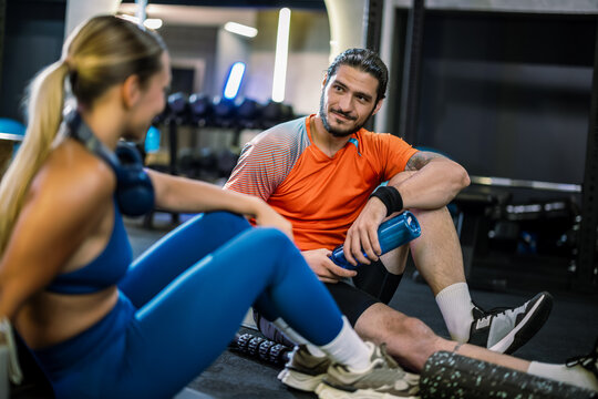 Athletic partners enjoying a post-workout break with shakes and neck headphones