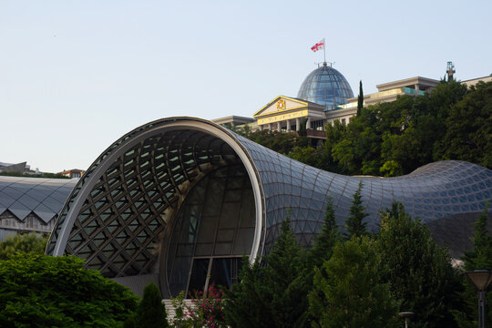 Tbilisi, Georgia - July 29, 2026: Street city photo. View of concert music theatre exhibition hall in shape of two metal glass tubes of hi-tech architecture style in Rike park and President palace