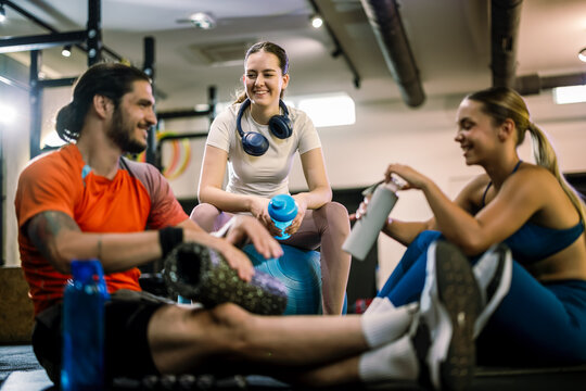 Fit group resting on gym mats with foam roller and yoga ball