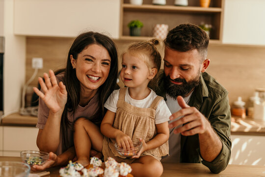Happy family baking cupcakes in modern kitchen