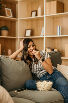 Woman relaxing at home watching movie eating popcorn