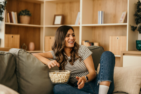 Young woman enjoying popcorn while relaxing at home