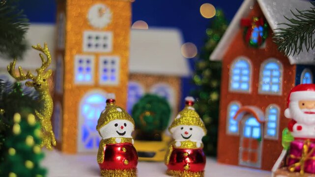 Two snowmen and Santa Claus in front of Christmas houses in Christmas town