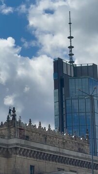 Worker cleaning decorative architectural elements on the rooftop of a historic building in Warsaw, Poland. Maintenance of historic architecture and urban building exterior against a modern city skylin