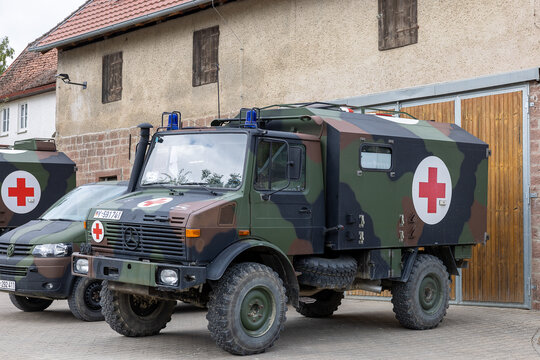 Mercedes-Benz Unimog in Flecktarn-Lackierung als Sanit&auml;tskraftwagen der Bundeswehr, gekennzeichnet mit Rotem Kreuz und Blaulicht.  