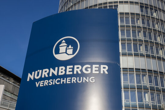 Blaues Stele-Schild der N&uuml;rnberger Versicherung mit Logo und Schriftzug vor dem Business Tower. Das Firmenschild zeigt das charakteristische Burgmotiv des Versicherungskonzerns.