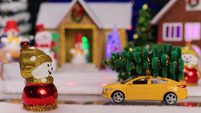 Against the backdrop of a small Christmas village, a yellow car drives up to a snowman