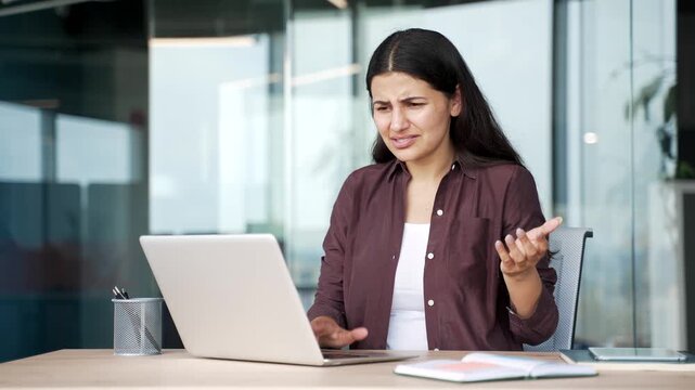 Worried disappointed businesswoman having problems with software on laptop sitting at workplace in business office. Frustrated angry female employee has issue with the task on computer