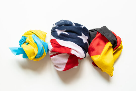 The flags of Ukraine, the United States, and Germany are folded and laid out on a white background, symbolizing international friendship, partnership, cooperation, unity