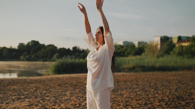 Calm woman doing mindful breathing exercises on the beach at golden hour.