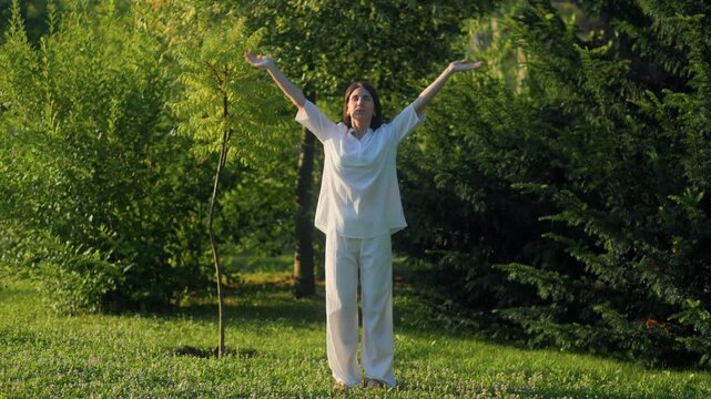 Serene adult woman practicing mindful breathing exercises in a green park.