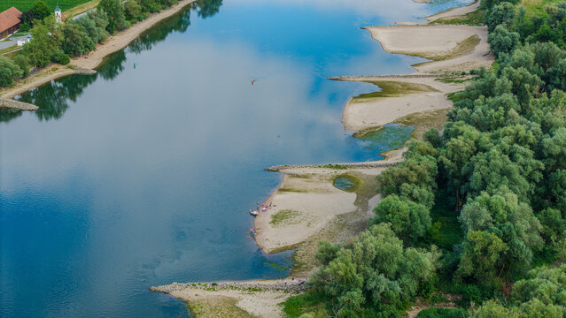 Flusslandschaft mit Sandb&auml;nken und B&auml;umen in der N&auml;he eines kleinen Dorfes