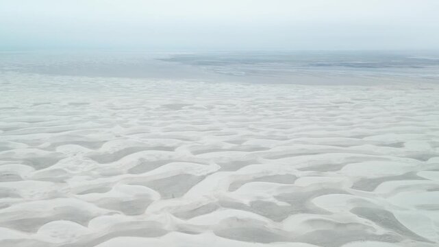 Cinematic aerial drone shot flying over the expansive white sand dunes and vast landscape of Guerrero Negro in Baja California Sur on a moody overcast day