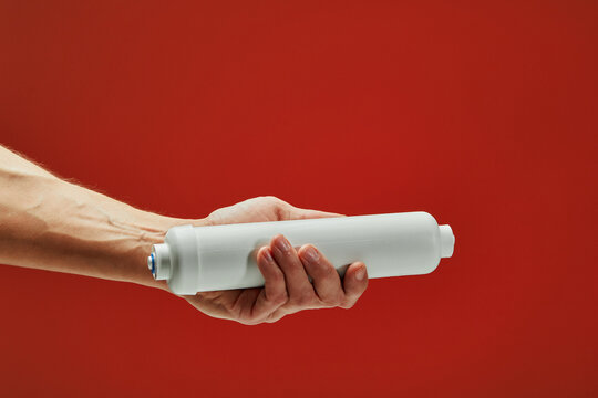 Close-up of a plumber holding a new water filter cartridge, emphasizing the importance of clean water and filtration systems