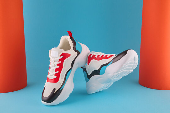 Colorful athletic trainers showcasing trendy design and chunky soles on a vibrant blue background with orange elements