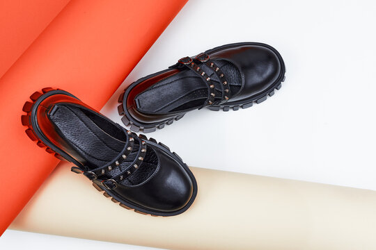 Black women's student shoes. Youth shoes in close-up. A pair of fashionable shoes for teenagers on an orange and white background.