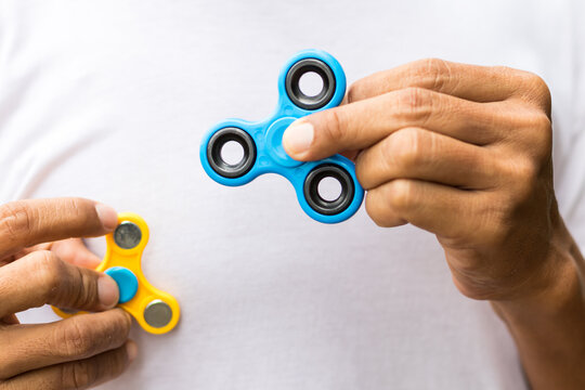 close up shot of a colorful fidget spinner with a black background in a studio setting image Close up image of a blue spinner in the left hand with the other one in the right hand. 
